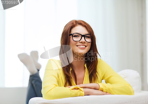 Image of smiling young woman lying on sofa at home