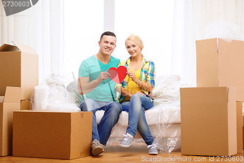 Image of smiling couple with red heart on sofa in new home