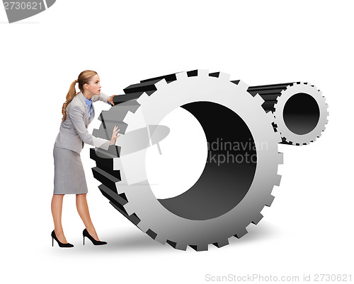 Image of busy businesswoman pushing cogwheel