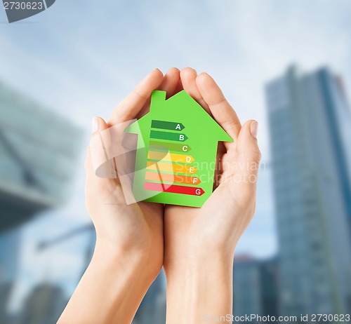 Image of hands holding green paper house