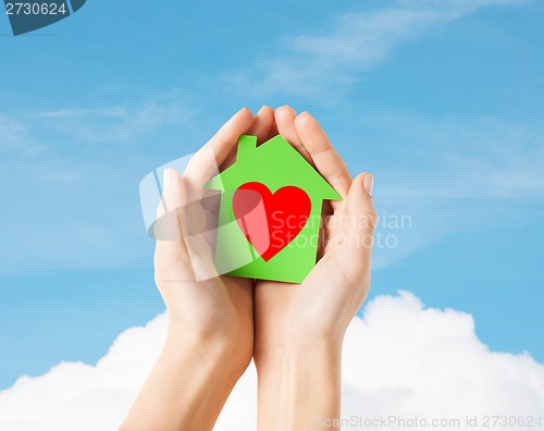 Image of hands holding green paper house