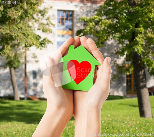 Image of hands holding green paper house