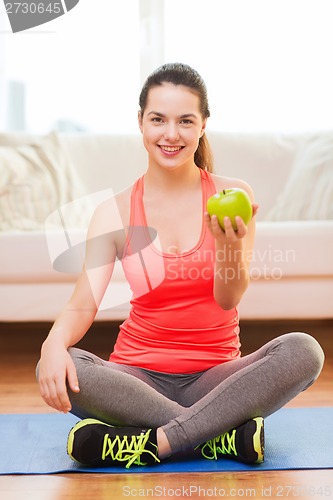 Image of smiling teenage girl with green apple at home