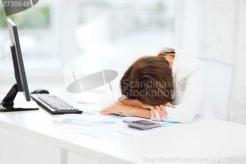 Image of stressed woman with computer, papers, calculator