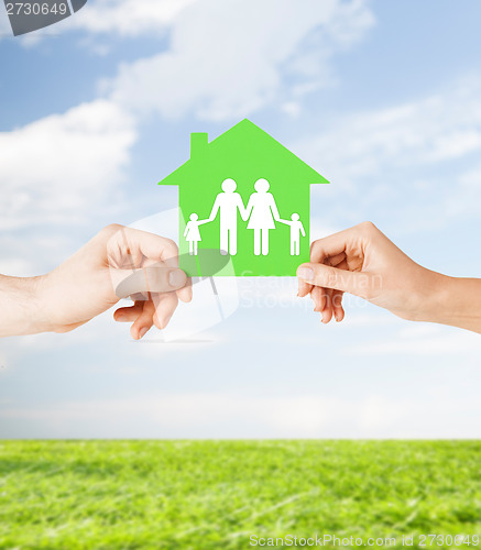 Image of hands holding green house with family