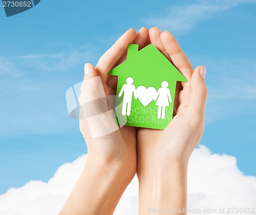 Image of hands holding green house with family