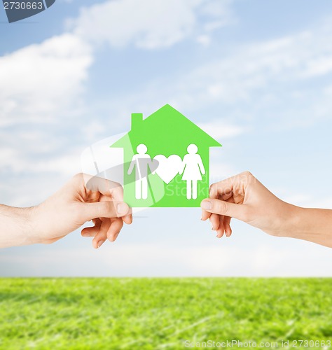 Image of hands holding green house with family