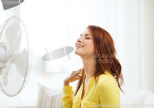 Image of smiling redhead teenage girl with big fan at home