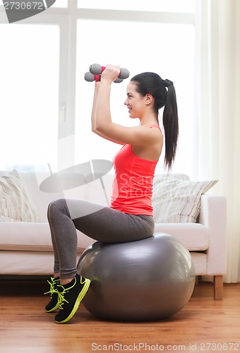 Image of smiling girl exercising with fitness ball
