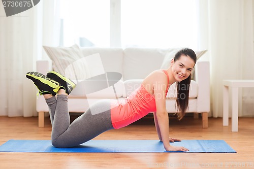 Image of smiling teenage girl doing push-ups at home