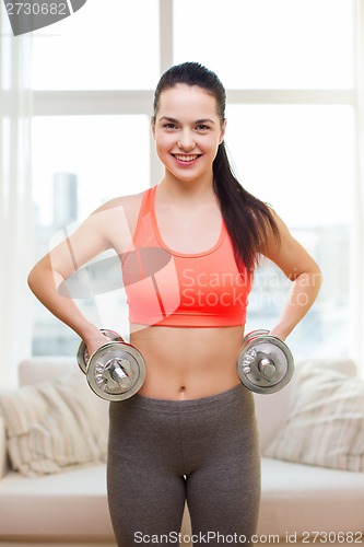 Image of smiling girl exercising with dumbbells