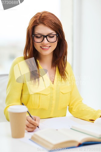 Image of smiling student girl reading books in library