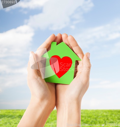 Image of hands holding green paper house