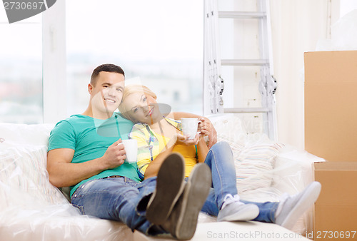 Image of smiling couple relaxing on sofa in new home