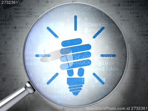 Image of Finance concept: Energy Saving Lamp with optical glass on digital background
