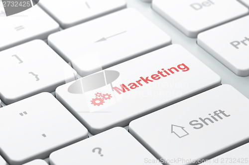 Image of Advertising concept: Gears and Marketing on computer keyboard background