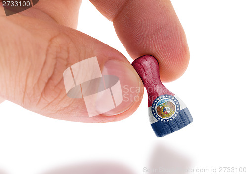 Image of Hand holding wooden pawn, flag painting, selective focus