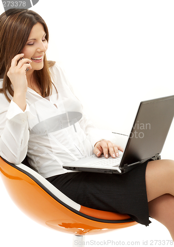 Image of businesswoman with laptop and phone in orange chair