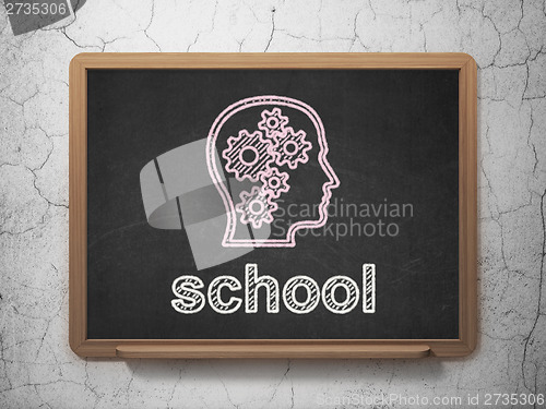 Image of Education concept: Head With Gears and School on chalkboard