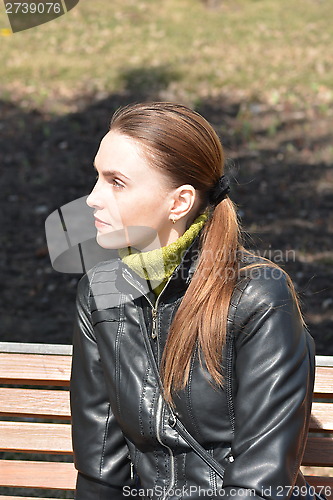 Image of Woman sitting on a bench in a sunny day