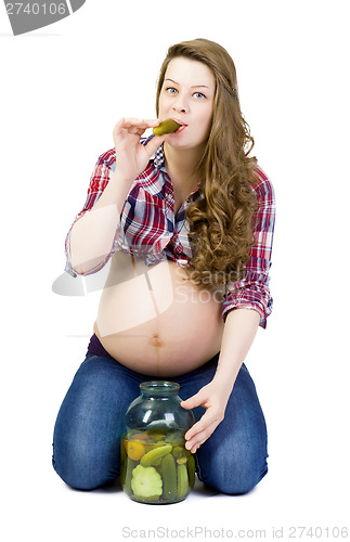 Image of Pregnant young woman on a white background eats pickled cucumber