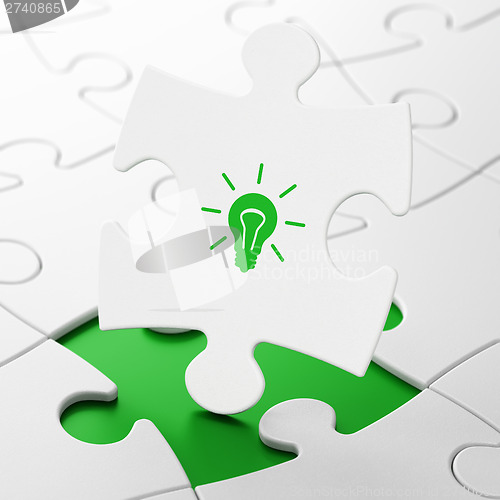 Image of Finance concept: Light Bulb on puzzle background