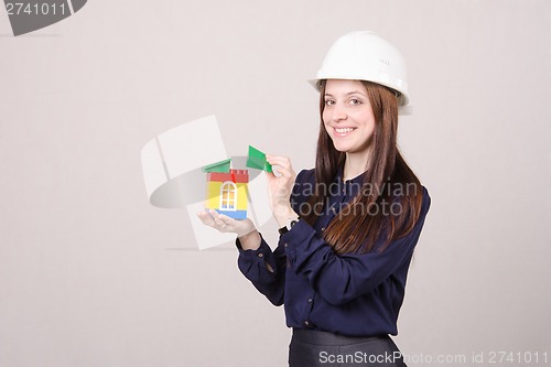 Image of Young girl standing with a house builder in hands of