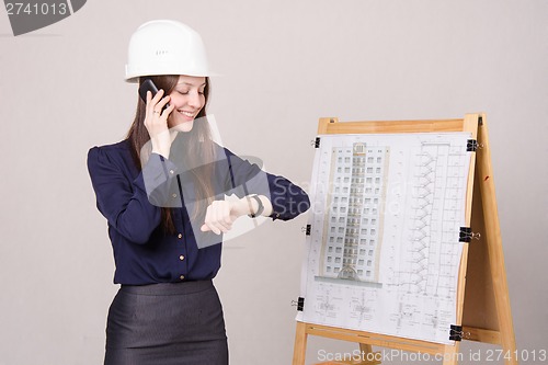 Image of Girl in helmet talking phone and looking at his watch