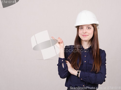 Image of Woman engineer in helmet points finger to right