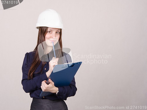 Image of Builder in helmet writes pencil folder