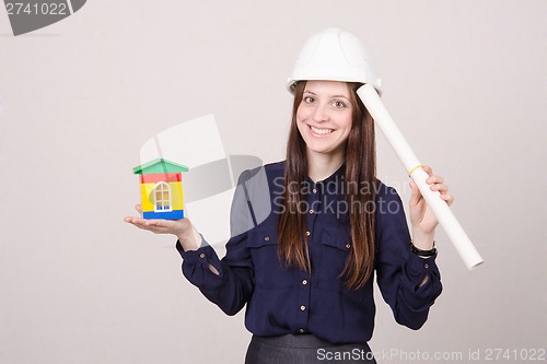 Image of young girl stands with house and drawing in hands of
