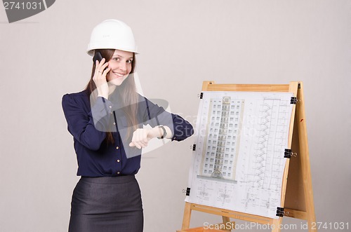 Image of Architect girl talking on phone and looking at his watch