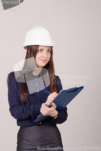 Image of Girl a helmet writes in pencil folder