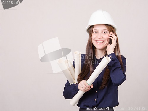 Image of Engineer talking on phone with blueprints in hand