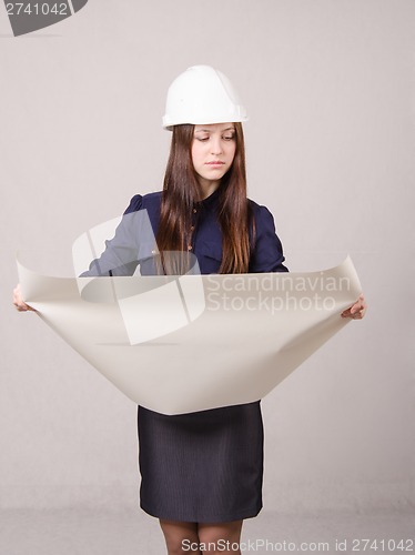 Image of Girl in helmet looks a project expanding hands drawing