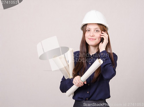 Image of Architect talking on phone with blueprints in hand