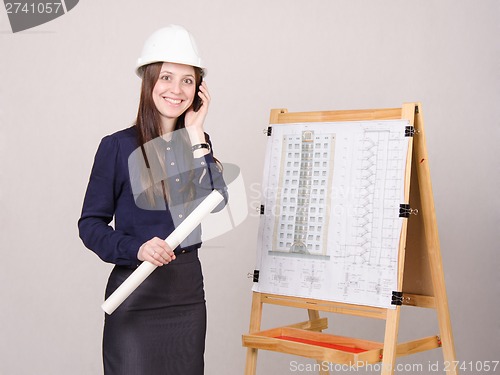 Image of Girl a helmet talking on phone with drawing in hands