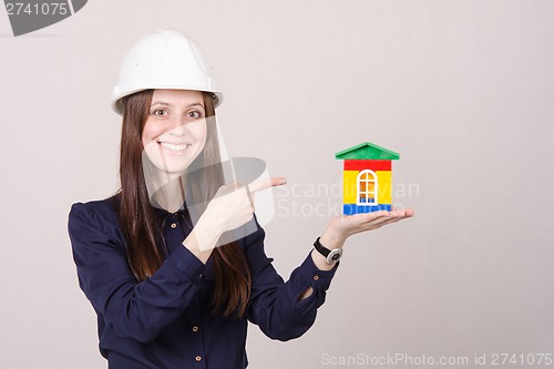 Image of Beautiful girl in helmet points to house layout