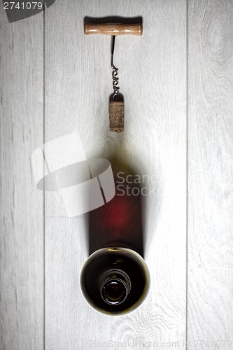 Image of Bottle of red wine with cork on white wooden table