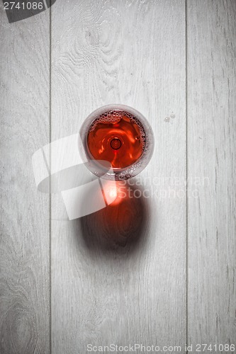 Image of Glass of red wine on wooden table.