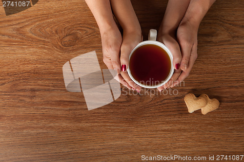 Image of Womans and mens hands holding hot cup of tea