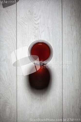 Image of Glass of red wine on wooden table.