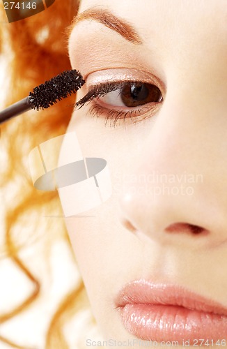 Image of lovely redhead applying black mascara
