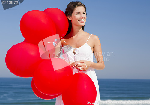Image of Beautiful girl holding red ballons