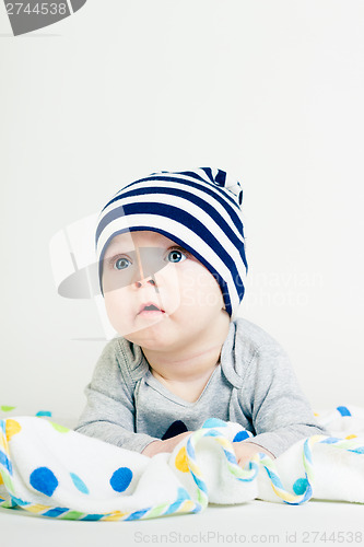 Image of cute baby in striped hat lying down on a blanket