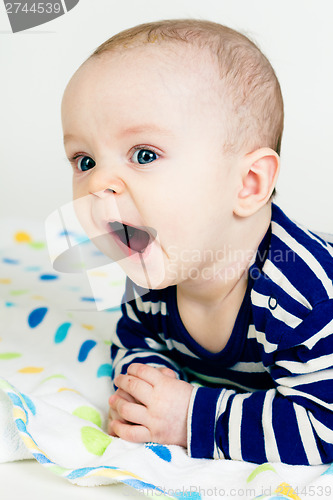 Image of cute baby in striped clothes lying down on a blanket