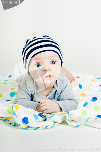 Image of cute baby in striped hat lying down on a blanket