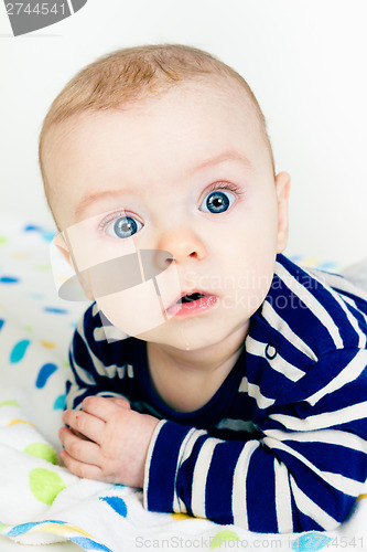 Image of cute baby in striped clothes lying down on a blanket