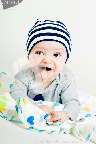 Image of cute baby in striped hat lying down on a blanket