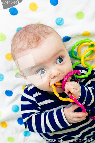 Image of cute baby in striped clothes lying down on a blanket